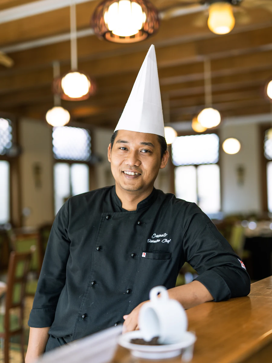 A chef in a black jacket leaning on a counter