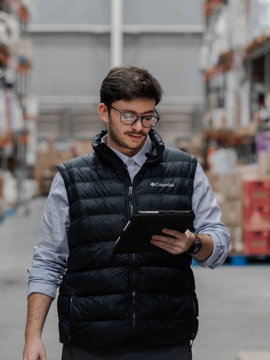 A warehouse worker in a vest holding a tablet